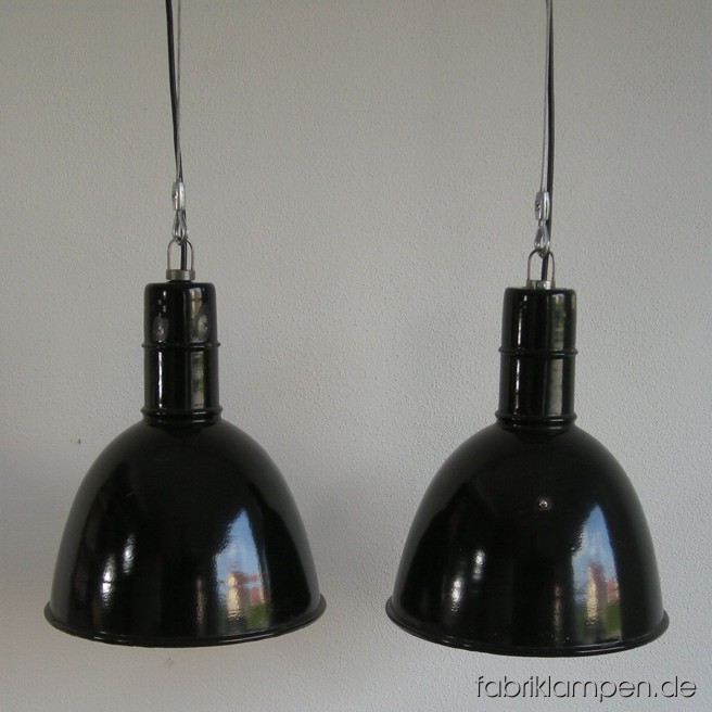 Schwarze Emaille Fabriklampen mit Drahtseil-Aufhängungen. Die Lampen sind gereinigt, neu elektrifiziert und getestet – sie haben eine E27 Fassung, also Sie können die Lampen mit normalen E27 Glühbirnen benutzen. Gesamthöhe: ca. 33,5 cm, Durchmesser Schirm ca. 29 cm.