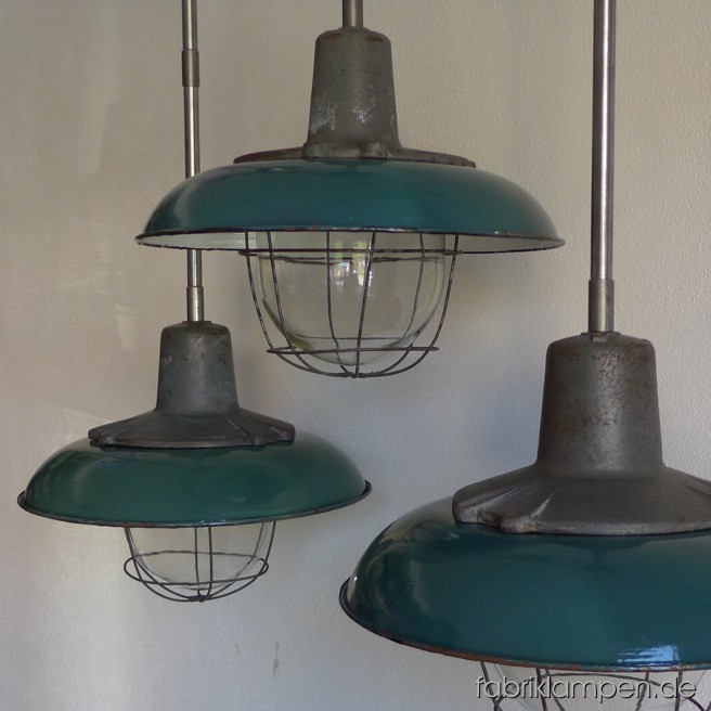 Factory lamps with green enamel shades and safety glasses (with or without grids). Material: casted iron, steel, glass and green enameled sheet. Newly electrified, with steel suspension. Height of the lamps ca. 34 cm (13,4 inches), diameter of the shades ca. 42 cm (16,5 inches), total height with suspension 91 or 65 cm (35,8 – 25,6 inches).