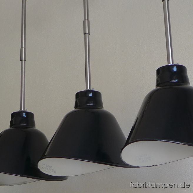 Rare old black enamel design factory lamp produced by VEB Leuchtenbau Leipzig (LBL). The asymmetric shades are elegant and functional over a long table, sideboard, bar or counter. The lamps have the typical traces of usage and age. Material: black (inside white) enameled steel sheet. Newly electrified, with E27 ceramic sockets. Height of the lamp ca. 26 cm (10,2 inches), width of the shade ca. 38,5 cm (15,2 inches), depth oft he sahe ca. 26 cm (10,2 inches). Total height with steel tube suspension and canopy 81 cm (32 inches). The lamps can be shipped also with suspension eye and cable (textile cable).