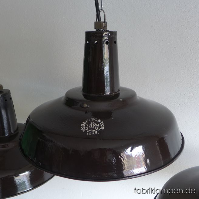 Old black enamel industrial lamps with hallmark. The lamps have the strong traces of usage and age. Material: green (inside white) enameled steel sheet. The neck is perforated (for ventilation/cooling), inside with holders (for glass – the lamps well be shipped without glass). Newly electrified, with E27 ceramic sockets. We have 7 pieces on stock. Height of the lamps ca. 30 cm (11,8 inches), diameter of the shades ca. 46 cm (18,1 inches). We have also the smaller version in stock: diameter 39 cm (15,3 inches), height 24 cm (9,4 inches).