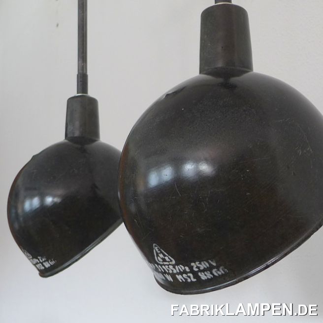 Asymmetric enamel lamps with steel-tube suspension and canopy. The enamel shades have the traces of usage and age. Material: black/anthrazite (inside white) enameled steel sheet. Cleaned and conserved, newly electrified, with E27 ceramic sockets. Suspension: steel-tube suspension and canopy. Diameter of the shade is ca. 26 cm (10,2 inches), total height of the lamps is 66 cm (26 inches). Longer suspension is possible. We have these lamps also in grayish blue in stock. The bigger version of the shades (diameter 31 cm, 12,2 inches) are also available. 