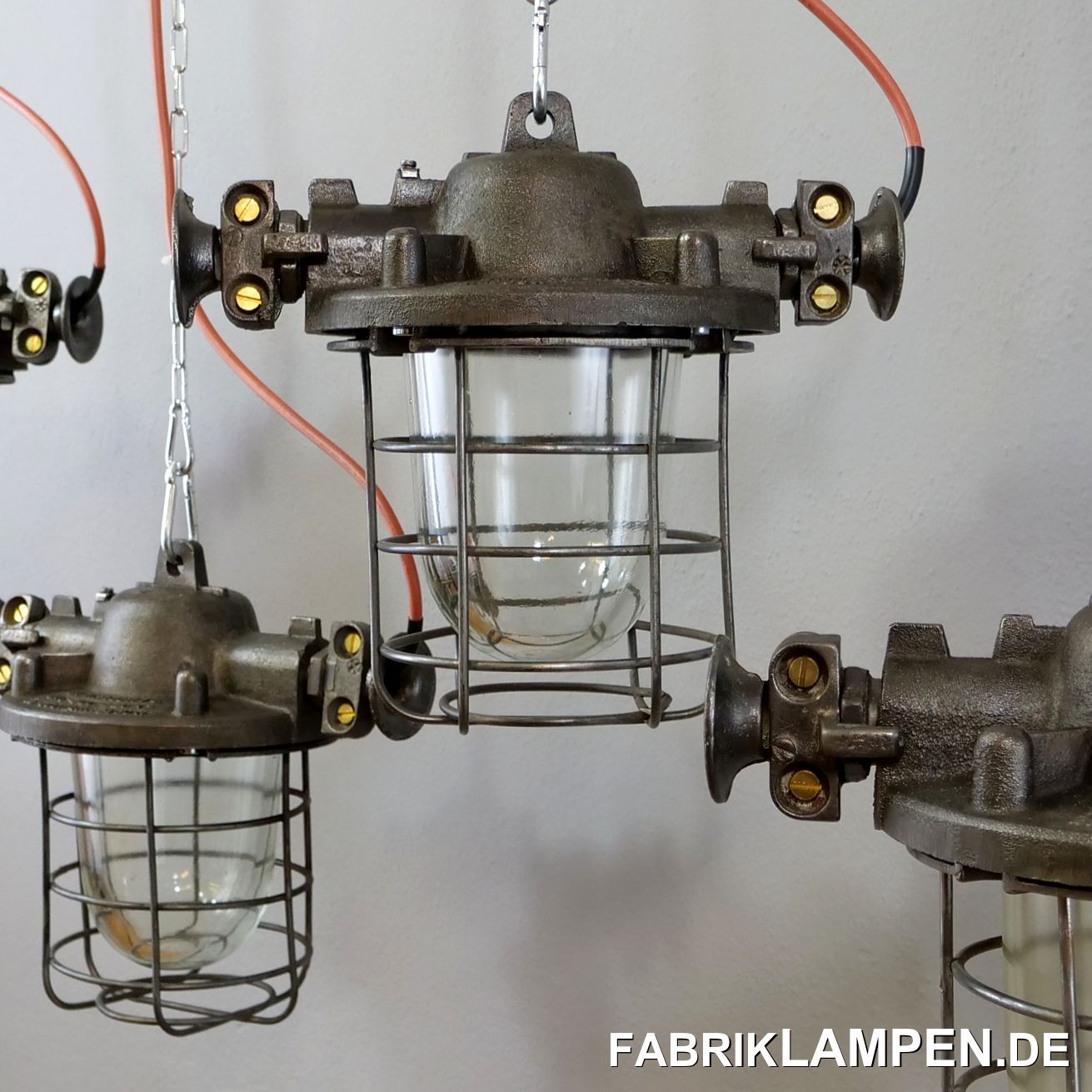  Old industrial lamp, bunker lamp made of cast steel with protective glass and grid. The factory lamps are refurbished. These old factory lamps are very robust in the structure and shape. The massive cable routings on the sides emphasize the strong industrial character. The bunker lamps are cleaned, refurbished (housing and grille ground), preserved and re-electrified (with new E27 ceramic sockets). Material: cast steel housing, steel grid, protective glass (thermoglass).Dimensions: Height of the lamps (with the suspension eye) 31 cm, diameter housing (without cable routing) about 23 cm, total width with the ears about 36 cm.Attention: the weight of the old industrial lamp is a proud 9.5 kg - the lamps need a load-bearing ceiling structure and massive chains for suspension. The old factory lamps are supplied with suspension eye and 2 meters of cable (other lengths are of course possible), on request they can be equipped with chain suspension (at extra cost). 